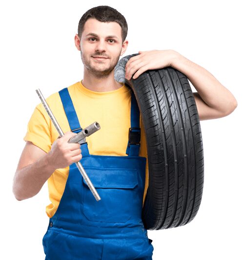 A mechanic of AK Fast Fit Tyres in Feltham carrying a part worn tyre for fitting on a car.