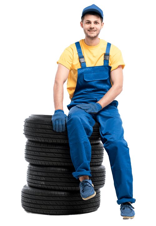 A mechanic of AK Fast Fit Tyres in Feltham sitting on new and part worn tyres.