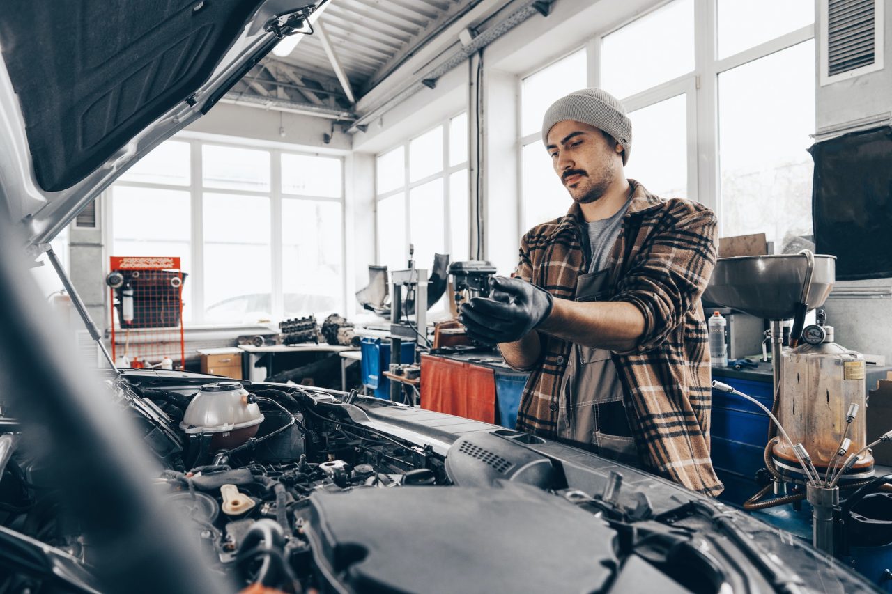 A mechanic of AK Fast Fit Tyres in Feltham doing mot and service for a car.